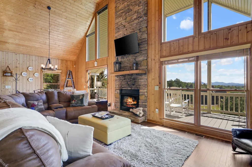 Great room with the stone fireplace and tall windows into the trees
