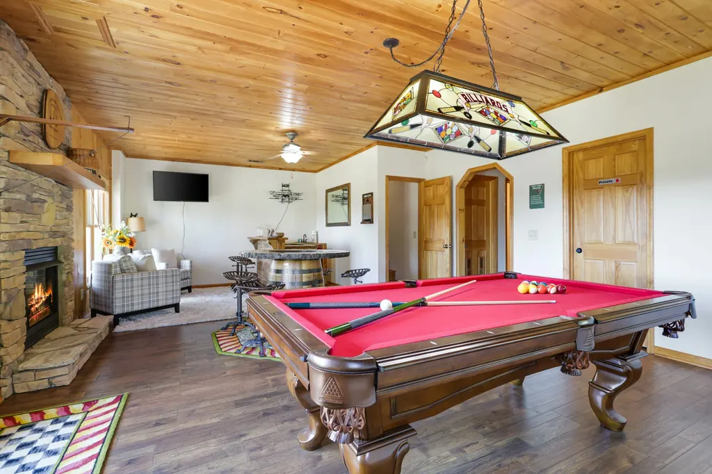 Lower-level game room with the pool table and stone fireplace